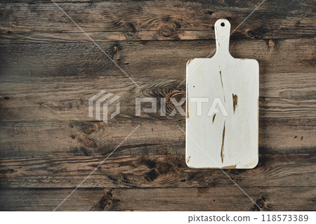 Vintage wooden cutting board on rustic wooden surface in a cozy kitchen setting 118573389