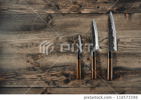 Three kitchen knives arranged on a rustic wooden surface in natural light Three kitchen knives arranged on a rustic wooden surface in natural light 118573398