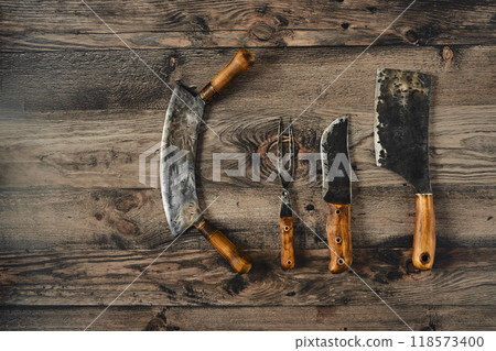 Set of vintage kitchen knives and butcher tools arranged on a rustic wooden surface Set of vintage kitchen knives and butcher tools arranged on a rustic wooden surface 118573400