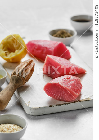 Fresh tuna steaks prepared for cooking alongside ingredients in a bright kitchen setting Fresh tuna steaks prepared for cooking alongside ingredients in a bright kitchen setting 118573408