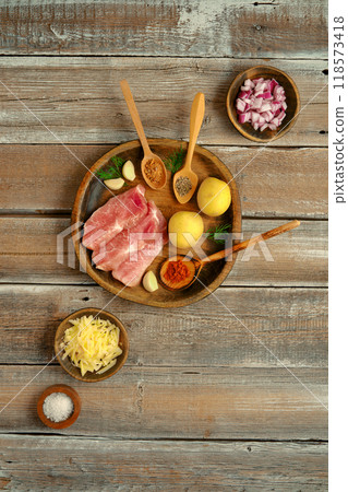 Preparing a hearty meal with fresh ingredients on a wooden surface in a cozy kitchen 118573418