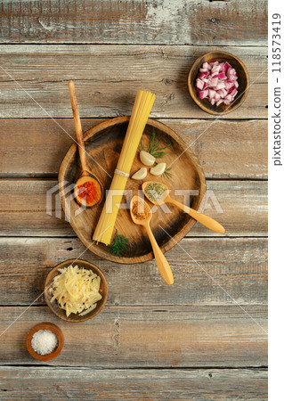 Fresh ingredients and spices laid out on a rustic wooden table ready for pasta preparation 118573419