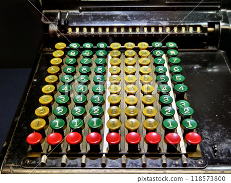 An old fashioned adding machine features a drawer located underneath it 118573800