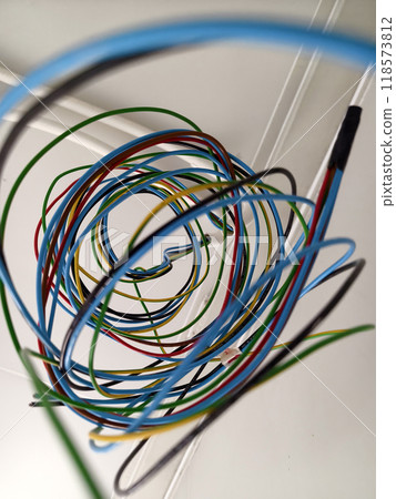 A collection of various wires is hanging down from the ceiling 118573812