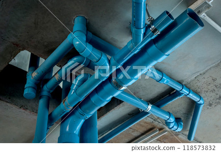A bright blue pipes attached to a solid concrete wall 118573832