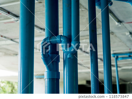 A bright blue pipes attached to a solid concrete wall 118573847