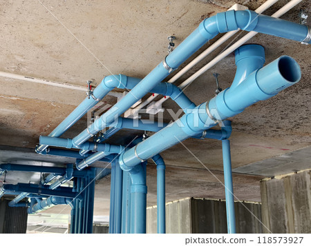 A bright blue pipes attached to a solid concrete wall 118573927