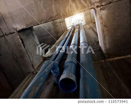 A bright blue pipes attached to a solid concrete wall 118573941