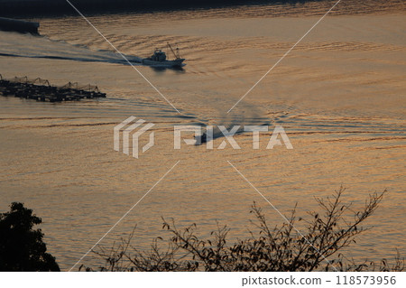 Silhouette of a fishing boat floating in the morning sun 118573956