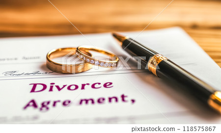 Divorce agreement being finalized with wedding rings on table Divorce agreement being finalized with wedding rings on table 118575867