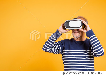 Portrait Asian smiling old man holding in a virtual reality glasses headset studio shot isolated yellow background, Excited happy senior man pensioner using VR play simulation game Portrait Asian smiling old man holding in a virtual reality glasses headset studio shot isolated yellow background, Excited happy senior man pensioner using VR play simulation game 118576039