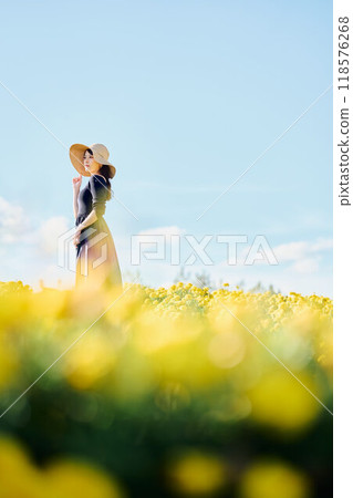 A woman wearing a hat standing in a flower field 118576268