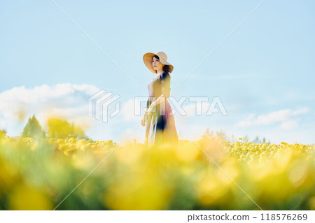 A woman wearing a hat standing in a flower field 118576269