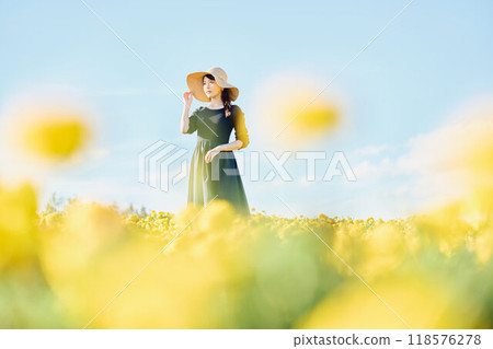 A woman wearing a hat standing in a flower field 118576278