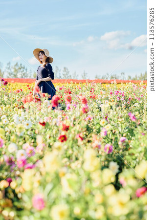A woman wearing a hat standing in a flower field 118576285