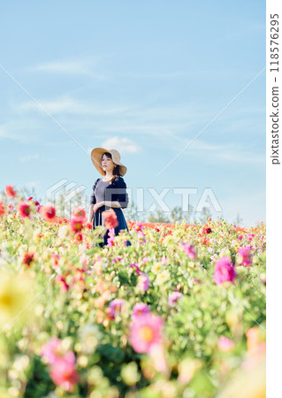 A woman wearing a hat standing in a flower field 118576295