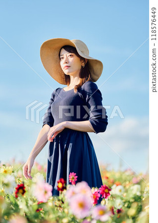 A woman wearing a hat standing in a flower field A woman wearing a hat standing in a flower field 118576449