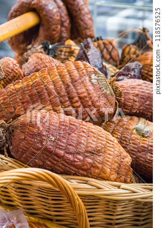 Fresh prepared smoked hams with spices in wicker basket on market stall Fresh prepared smoked hams with spices in wicker basket on market stall 118576525