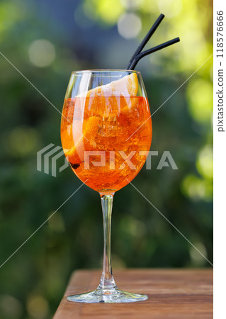 aperol spritz cocktail in glass on table with green background aperol spritz cocktail in glass on table with green background 118576666