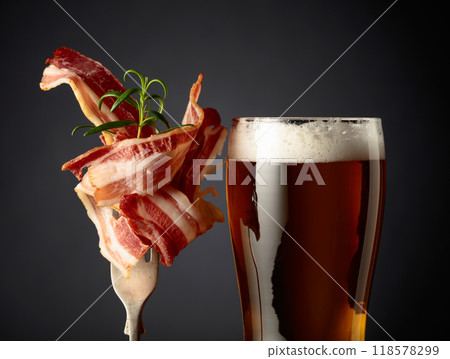 Beer and slices of  fried bacon garnished with rosemary. 118578299