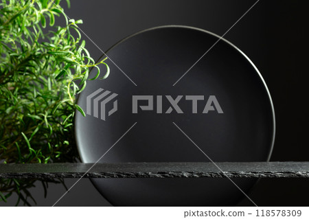 Black stone podium, black ceramic plate and branches of rosemary. 118578309