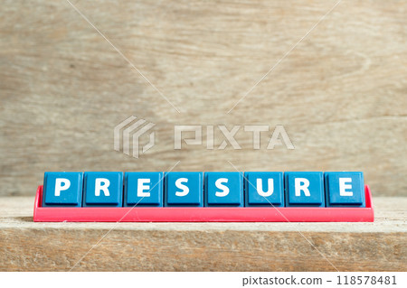 Tile letter on red rack in word pressure on wood background Tile letter on red rack in word pressure on wood background 118578481