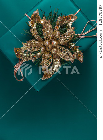 Christmas gift box with gold flower decoration, on green background Christmas gift box with gold flower decoration, on green background 118579897