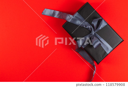 Black gift box with gray ribbon on red background for Christmas or Valentine 118579908