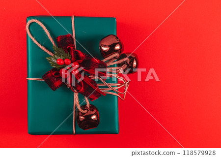 Green gift box with bow and bells on red background 118579928