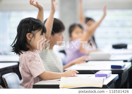 Elementary school students taking a class raise their hands and say "yes" Elementary school students taking a class raise their hands and say "yes" 118581426