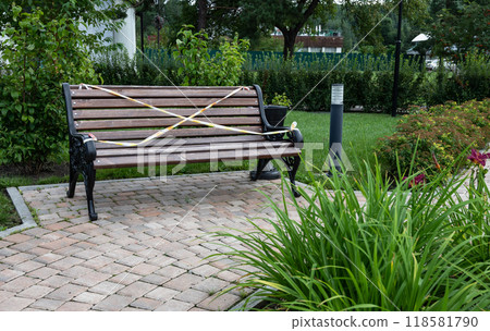 Park bench with caution tape in a garden setting. 118581790