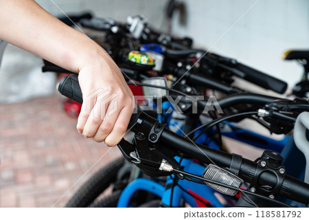 Hand gripping the brake lever of a bicycle handlebar in close-up. Hand gripping the brake lever of a bicycle handlebar in close-up. 118581792