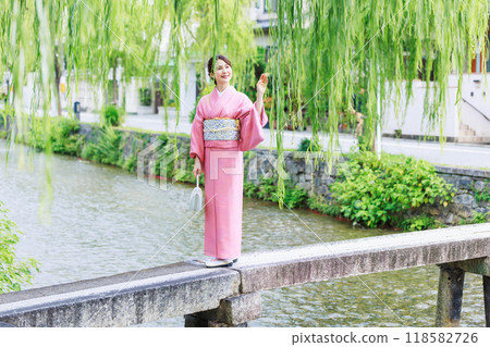 A woman in a kimono crossing a single bridge over the Shirakawa River in Kyoto 118582726