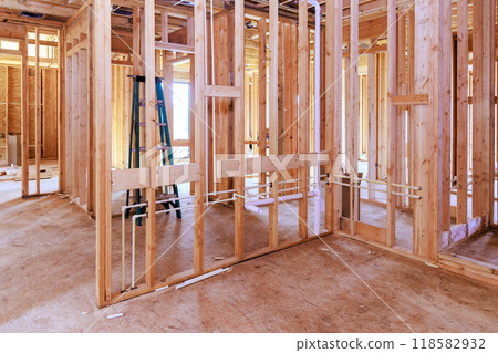 An unfinished interior of newly constructed house with wooden stud timber framing supporting beams An unfinished interior of newly constructed house with wooden stud timber framing supporting beams 118582932