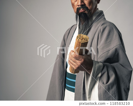 A scene of a Chinese historical figure, such as Zhuge Liang from the Romance of the Three Kingdoms, pondering while holding bamboo strips A scene of a Chinese historical figure, such as Zhuge Liang from the Romance of the Three Kingdoms, pondering while holding bamboo strips 118583210