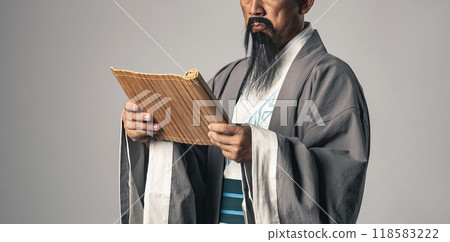 A scene in which a Chinese historical figure, such as Zhuge Liang from the Romance of the Three Kingdoms, reads characters written on bamboo slips. A scene in which a Chinese historical figure, such as Zhuge Liang from the Romance of the Three Kingdoms, reads characters written on bamboo slips. 118583222