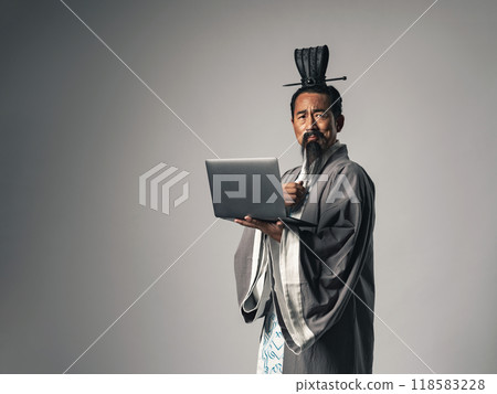 A scene where a Chinese historical figure, such as Zhuge Liang from Romance of the Three Kingdoms, uses a laptop A scene where a Chinese historical figure, such as Zhuge Liang from Romance of the Three Kingdoms, uses a laptop 118583228