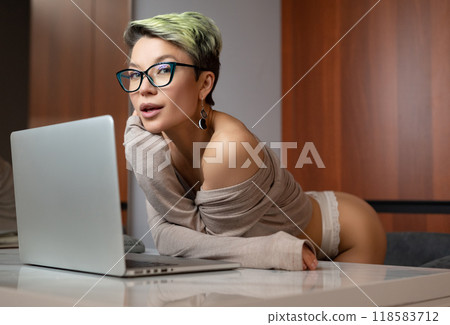 A beautiful girl with short hair in her underwear is sitting sexy in a room at a laptop, working and chatting online A beautiful girl with short hair in her underwear is sitting sexy in a room at a laptop, working and chatting online 118583712