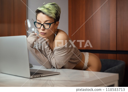 A beautiful girl with short hair in her underwear is sitting sexy in a room at a laptop, working and chatting online 118583713