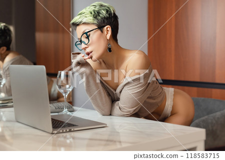 A beautiful girl with short hair in her underwear is sitting sexy in a room at a laptop, working and chatting online A beautiful girl with short hair in her underwear is sitting sexy in a room at a laptop, working and chatting online 118583715