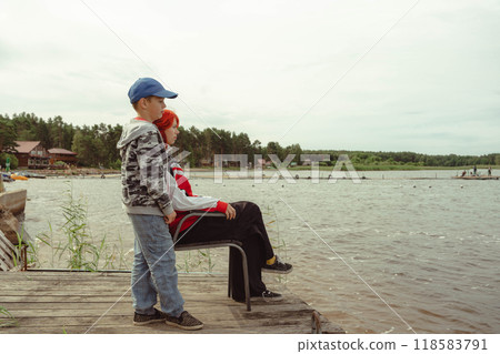 Generation Z redhead girl bonding with younger brother by the lake Generation Z redhead girl bonding with younger brother by the lake 118583791