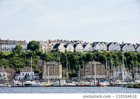 Rows of brick and triangular-roofed houses along the coast beside the yacht harbor and on the hills. A suburban townscape in South Wales. 118584618