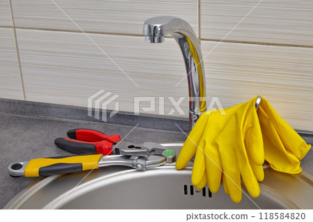 Yellow rubber gloves and tools for replacing kitchen sink faucet aerator 118584820