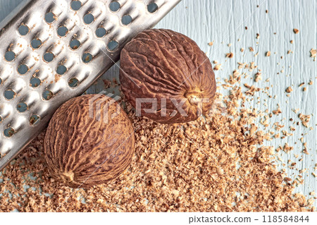 Whole nutmeg and metal grater on blue wooden table 118584844