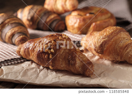 Freshly baked Almond Croissant. Arranged on a cloth and parchment paper. 118585848