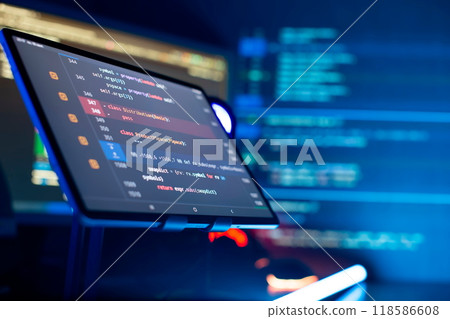 Programmer manually working with program code on a computer at night in a data center and technology concept. 118586608