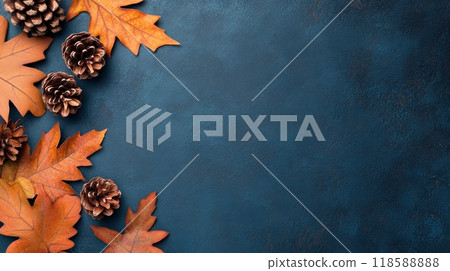 Autumn leaves and pine cones arranged on a textured blue background in a cozy indoor setting 118588888