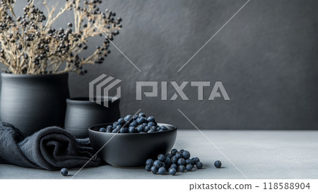 Elegant display of black seed oil and berries in dark ceramic pots on textured background 118588904