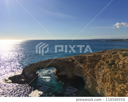 Love bridge near Ayia Napa in Cyprus. Natural rock arch Bridge of Lovers at Cape Greco. Sea caves on coastline between Agia Napa and Cavo Greco National park Love bridge near Ayia Napa in Cyprus. Natural rock arch Bridge of Lovers at Cape Greco. Sea caves on coastline between Agia Napa and Cavo Greco National park 118589358