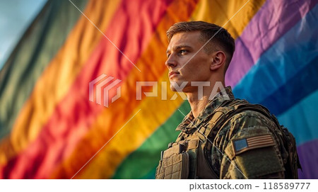 A soldier is proudly standing in front of a vibrant rainbow flag 118589777